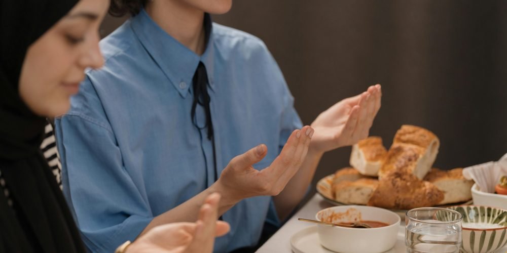 Women praying at a Ramadan meal, sharing food and cultural traditions.