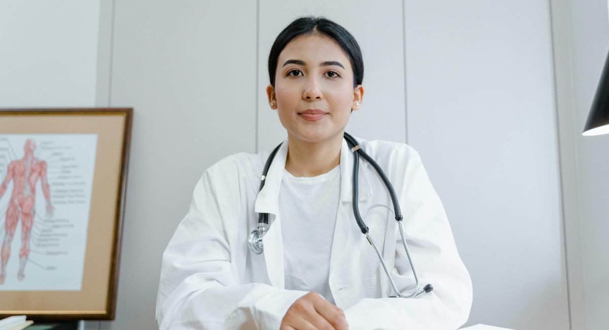 A female doctor confidently sits at her desk, ready for consultation in a medical office.